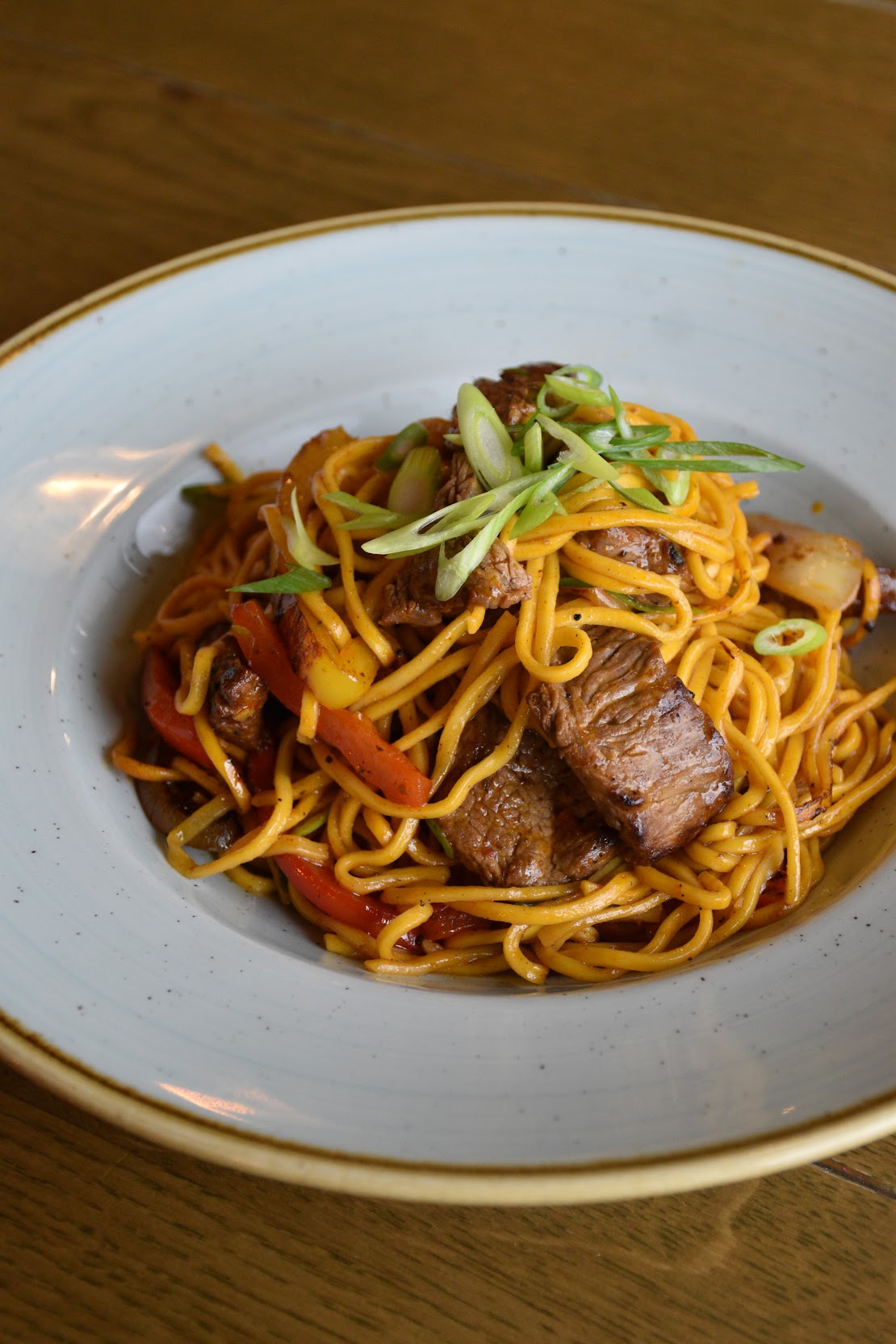 Beef Stir Fry Mix served with noodles, red peppers, and spring onions on a white plate.