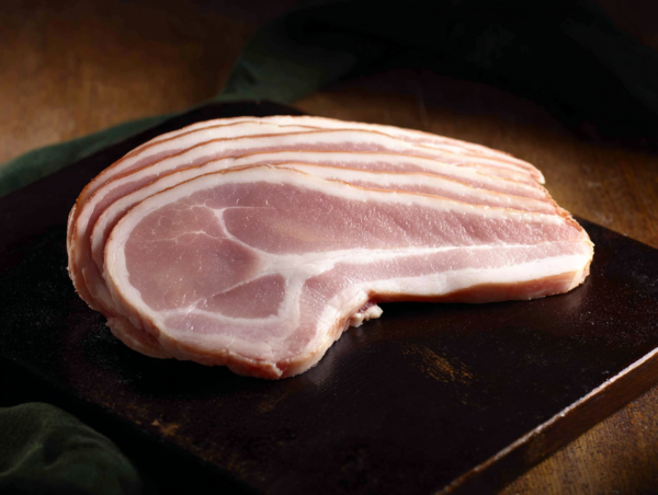 Four rashers of Beer Back Bacon stacked on a dark surface.