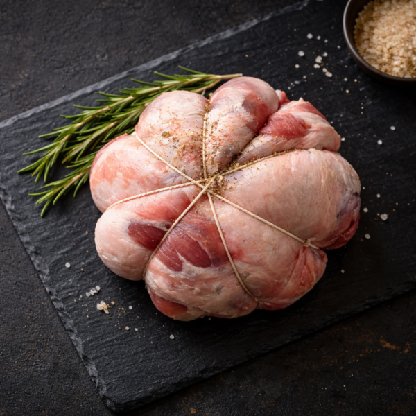 Lamb Shoulder 'En Balon' seasoned with pepper, salt, and rosemary on a black slate board.