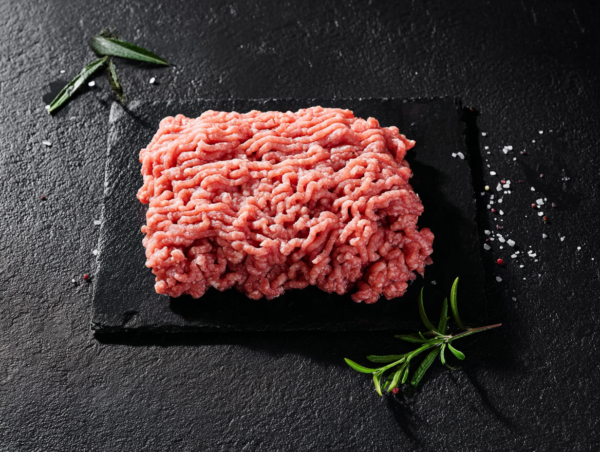 Pork Mince on a black slate, garnished with rosemary and sprinkled with salt.