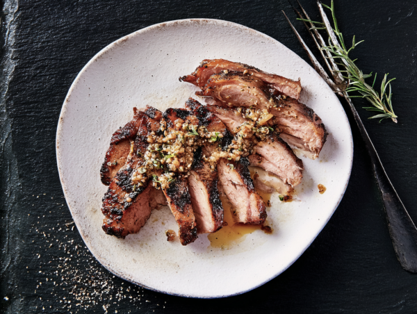 Pork Shoulder Steak with herb and garlic topping, served on a white plate and garnished with rosemary.