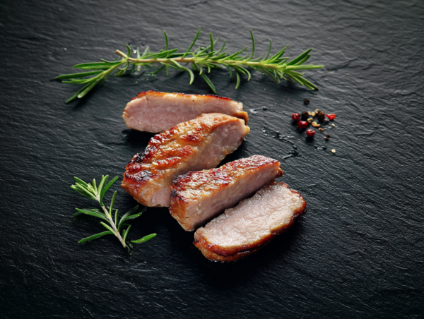 Three Pork Sirloin Steaks with grill marks on black slate, garnished with rosemary and peppercorns.