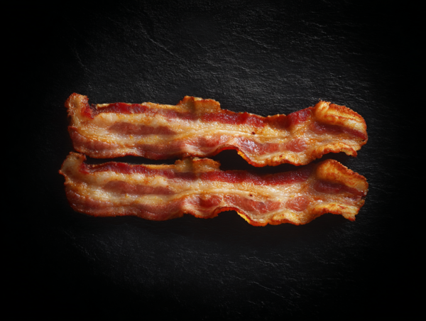 Two rashers of Smoked Streaky Bacon on a dark, textured background.
