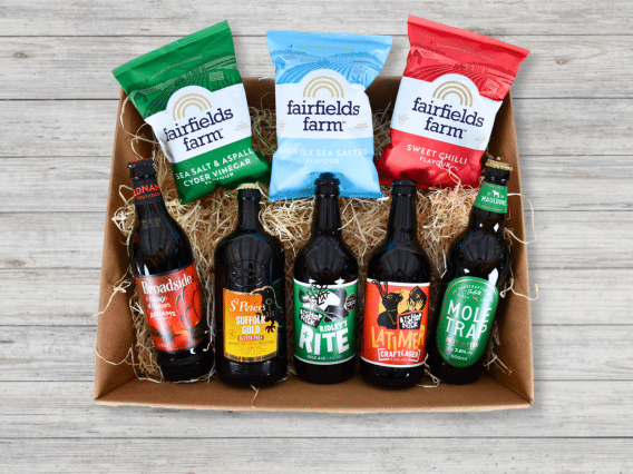 The Brewer’s Hamper (NEW): Six beers and three Fairfields Farm crisps on straw, arranged on a wooden surface.