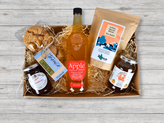 The Local Treats Hamper (NEW) includes apple juice, tea bags, jams, and a pastry in a cardboard tray.