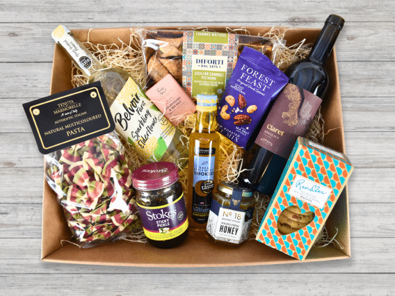 The Luxury Hamper (NEW): A gift box of gourmet foods, drinks, pasta, snacks & condiments on a wooden surface.