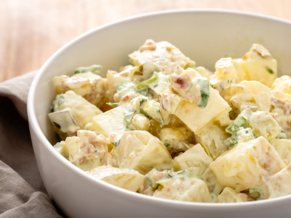 Potato Salad in a white bowl with chopped potatoes, herbs, and creamy dressing.