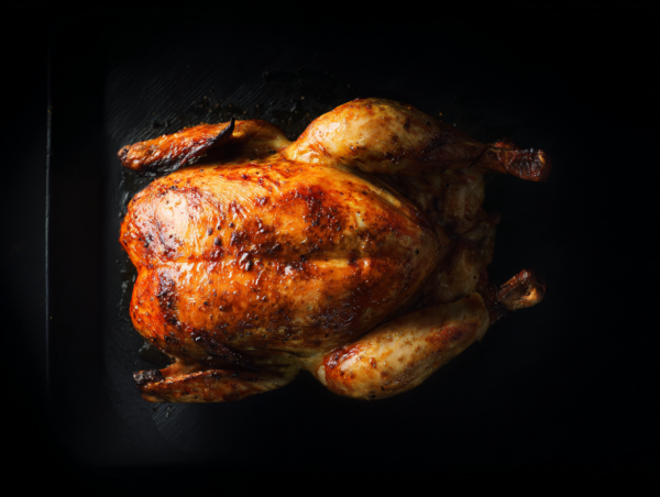 Whole Chicken roasted to golden, crispy perfection on a dark background.