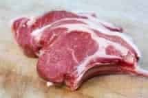 French trimmed lamb cutlets on a wooden chopping board.
