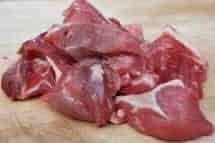 Diced lamb pieces on a wooden chopping board.