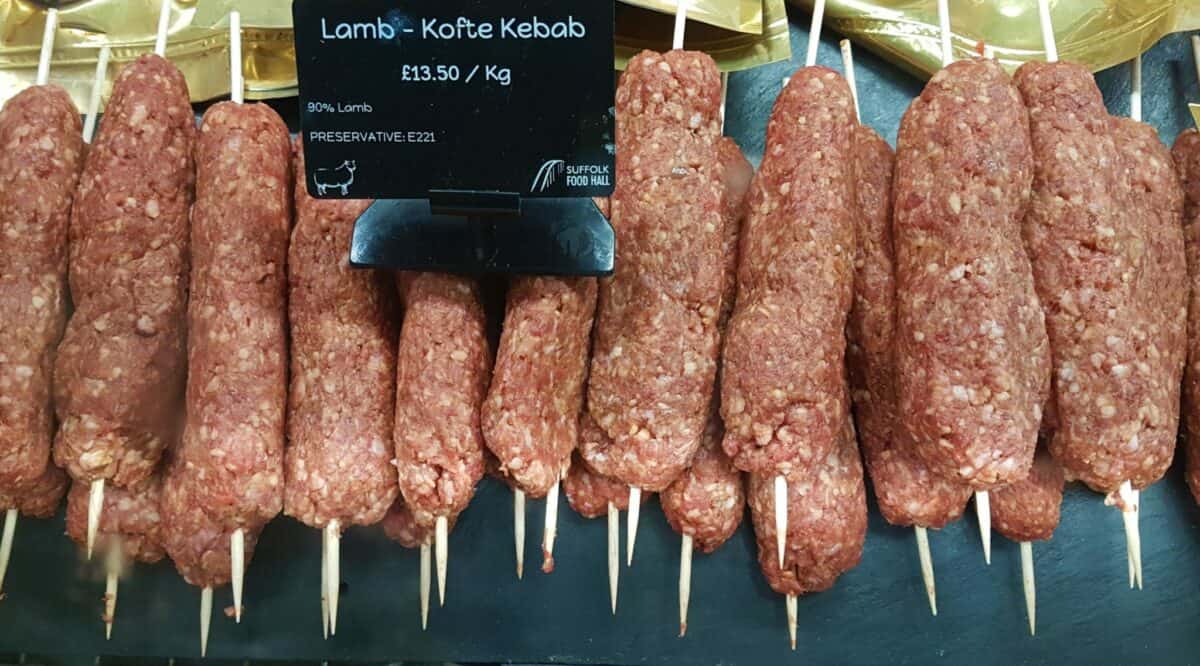 Lamb Kofta Kebab on skewers displayed for sale with a price sign above.